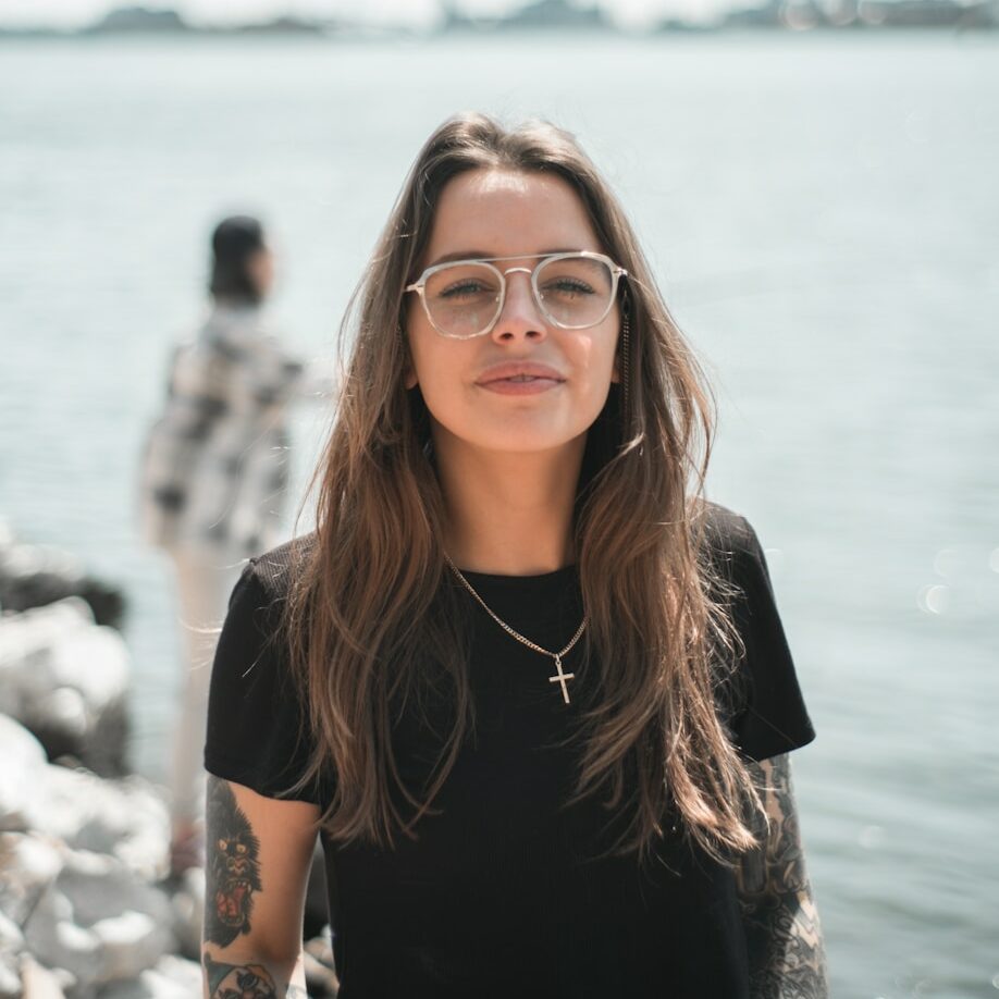 woman in black crew neck t-shirt wearing brown framed eyeglasses standing on rocky shore during